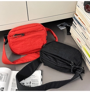 Detail view of red and black nylon crossbody bags with pleated texture and wide straps