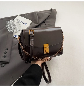 Détail du sac en cuir brillant marron foncé avec fermoir doré et bandoulière chaîne