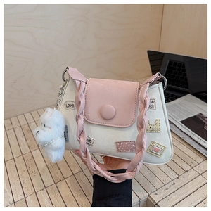 Detalle de un bolso cubo chic con parches de corazón, asa trenzada y colgante de oso