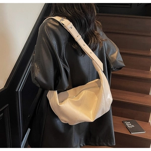 Detail view of cream-colored soft leather crossbody bag with wide shoulder strap