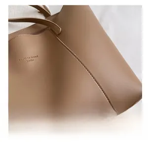 Gros plan du logo doré et des coutures sur un grand sac cabas marron en cuir