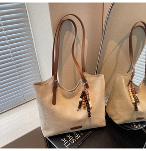 Detail of minimalist beige suede tote bag with brown leather strap and wood bead charm