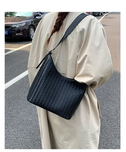 Outdoor shot showing a black woven shoulder bag with large capacity and leather strap