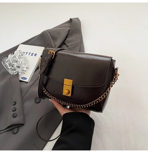 Détail du sac bandoulière en cuir marron foncé avec fermoir doré carré classique