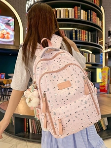 Pink star pattern school backpack with large capacity and cute plush pendant in a library