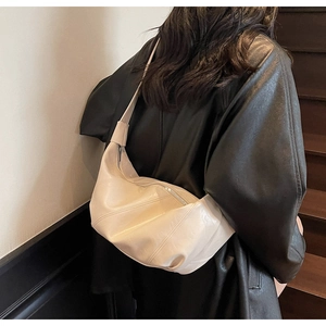 Close-up of cream textured faux leather hobo bag with diagonal pleated stitching and strap