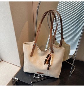 Detail of suede tote bag with brown leather straps and colorful wooden bead charms
