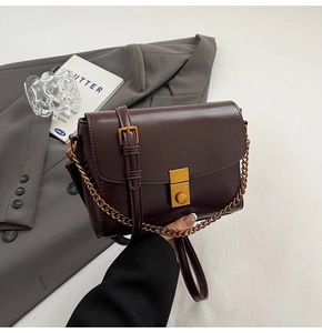Détail du sac bandoulière marron foncé avec boucle dorée vintage et bandoulière chaîne