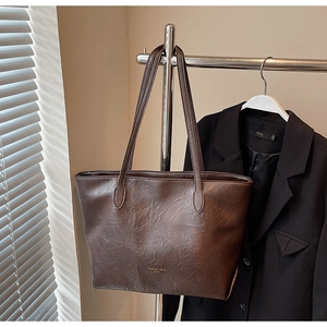 Close-up of deep brown leather tote bag detail with golden fashion trend lettering