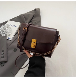 Détail du sac en cuir marron vintage avec boucle dorée mate et chaîne métallique