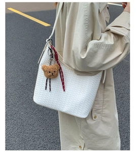 Detailed weave texture of a white handmade bucket bag with a cute bear plush charm