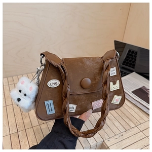 Detalle de bolso vintage de ante marrón con bordados coloridos y un colgante de perro de felpa