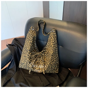 Détail d'un sac cabas léopard avec slogan blanc et fermeture par cordon à nœud