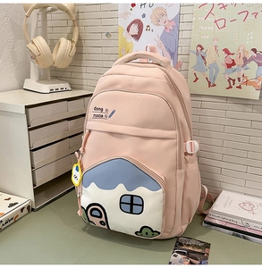 Detail of pink student backpack featuring a unique house-shaped pocket and cute plush charm