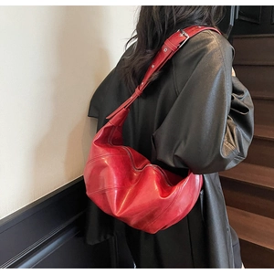 Macro detail of red crescent hobo bag with adjustable strap worn as a crossbody