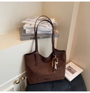 Detailed shot of dark brown suede tote bag with stylish beaded tassel and slim straps