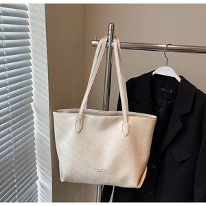 Detailed view of the creamy beige tote bag showing its pleated texture and gold lettering