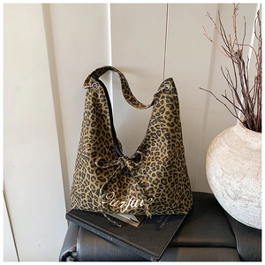 Détail du sac cabas en toile à motif léopard avec nœud papillon et lettrage