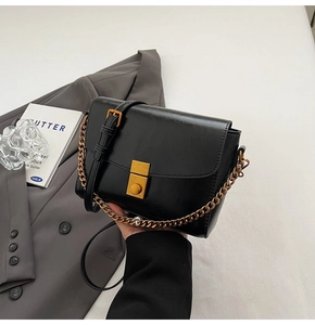 Détail du sac à bandoulière noir brillant avec fermoir doré et bandoulière chaîne