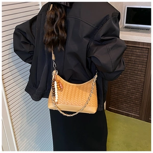 Detail of woven khaki hobo bag featuring metal chain and bohemian bead tassel accessory