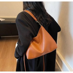 Détail de texture tressée sur grand sac porté épaule caramel avec crochet doré