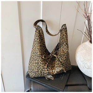 Gros plan du sac cabas léopard avec un détail de nœud latéral et lettrage artistique