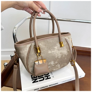 Close-up of beige velvet bucket bag featuring mini charm and matte gold hardware details