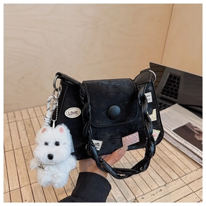 Detalle de bolso bucket de ante negro con parches coloridos y colgante de peluche