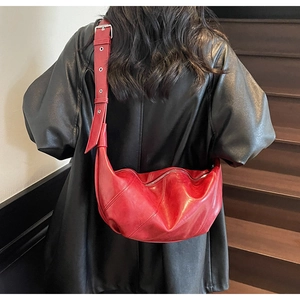 Detail of red crescent shoulder bag with vintage texture and silver buckle on adjustable strap