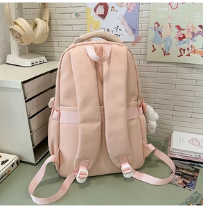 Detail of ergonomic padded shoulder straps and cute bear keychain on a pink school backpack