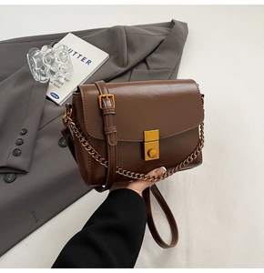 Détail d'un sac à bandoulière en cuir café brillant avec un fermoir doré métallique