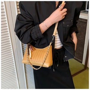 Detail of light brown woven crossbody bag with beaded tassel and metal chain strap