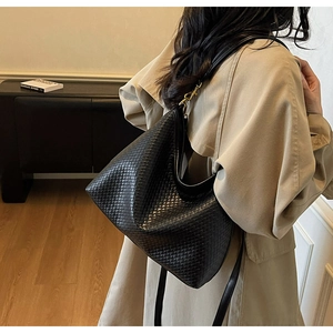 Détail d'un grand sac cabas en cuir tressé noir avec des finitions métalliques dorées