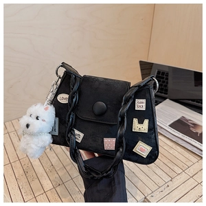 Detalle de bolso de hombro de ante negro con bordados y colgante de perro de peluche