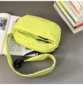 Detail view of neon green nylon crossbody bag with dual zippers and woven label