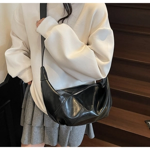 Detail showing the actual fit of the black leather crescent crossbody bag on a model