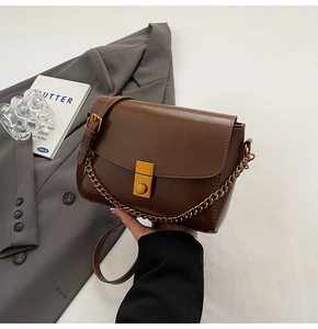 Détail d'un sac à bandoulière marron vintage en similicuir avec boucle dorée et chaîne