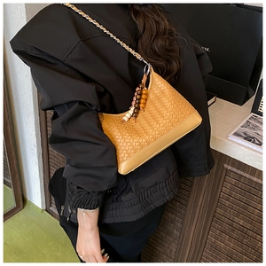 Detail of woven hobo bag featuring beaded tassel charms and silver chain strap