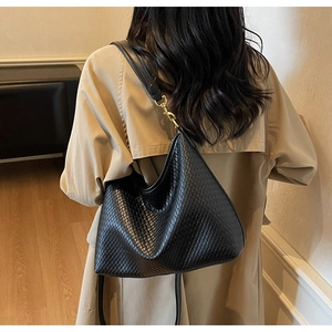 Détail du sac hobo en cuir tressé noir avec boucle dorée et longue bandoulière en cuir