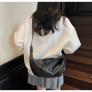 Detail of black PU leather crescent bag with diagonal stitching and silver zipper