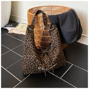 Gros plan d'un sac cabas léopard avec broderie One Love et anneaux métalliques