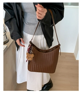 Detail of dark brown woven Hobo bag with plush bear charm and matching shoulder strap