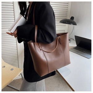 Détail d'un grand sac cabas marron sur un mannequin dans un cadre de bureau moderne