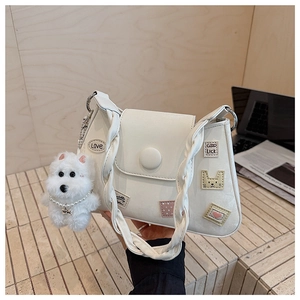 Detalle de bolso de hombro en cuero blanco con parches bonitos y colgante de peluche