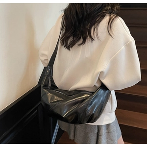 Detail of a black pleated crescent bag shown on a model for size and slouchy style
