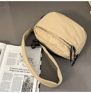 Detailed view of beige nylon crossbody bag with double zippers and soft texture fabric