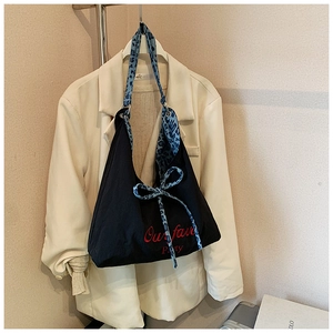 Détail du sac fourre-tout en toile noire avec broderie rouge et sangle léopard bleue