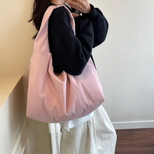 Détail du sac à bandoulière en velours côtelé rose montrant la texture sur un modèle