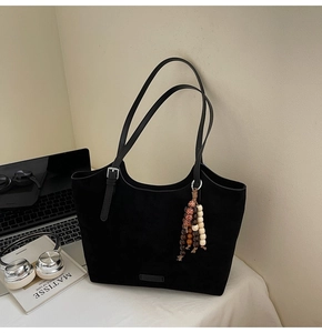 Large black suede tote bag with ethnic beaded tassel and minimalist office accessories