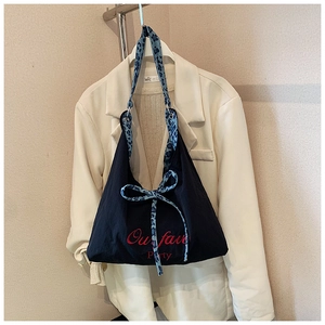 Détail du sac en toile noire avec nœud léopard bleu et broderie rouge artistique